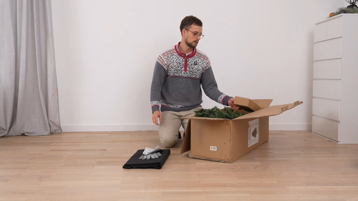 Aaron Berndt packt den Weihnachtsbaum aus dem Karton aus, Standbild aus dem Aufbauvideo